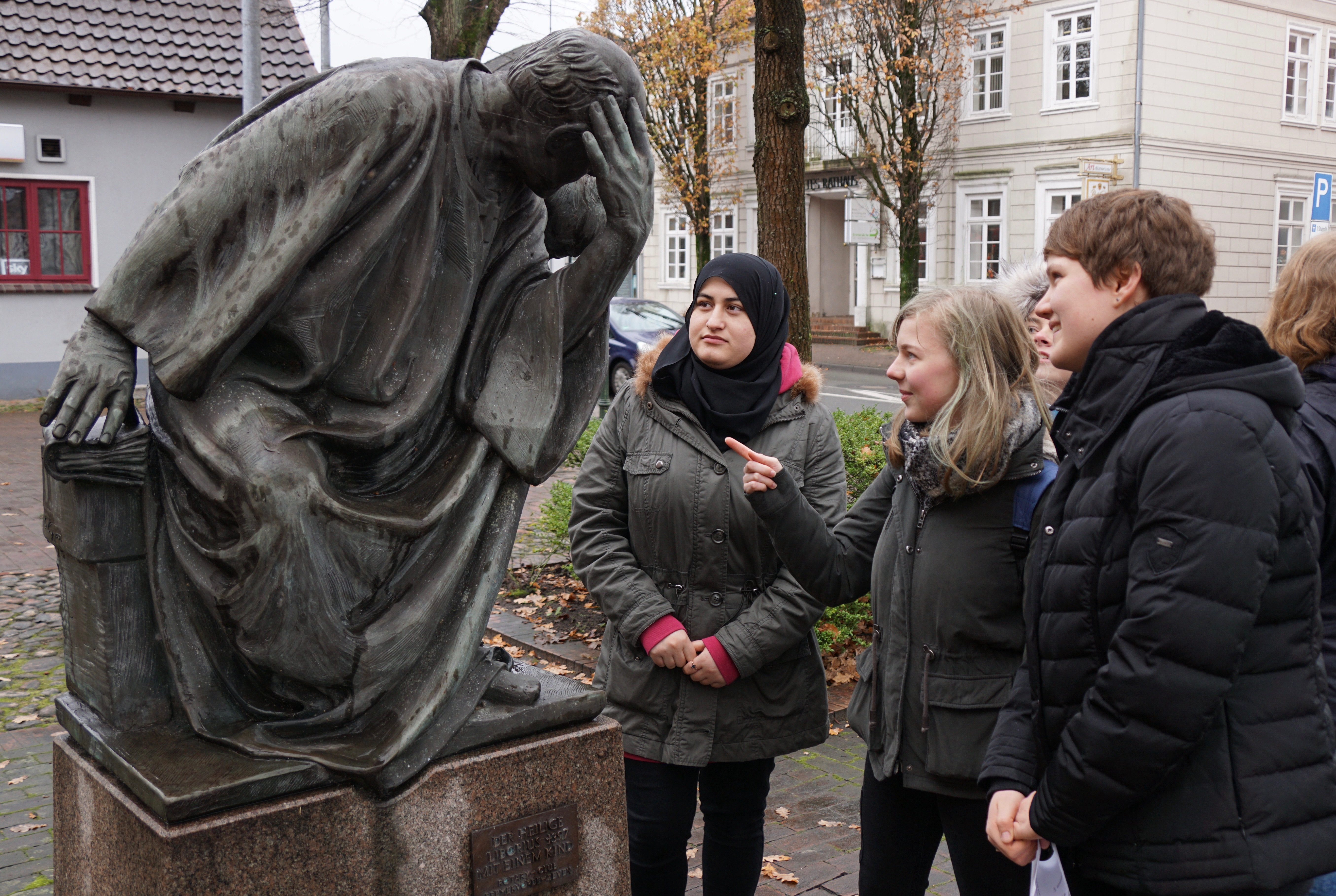 Drei Schülerinnen betrachten die Liborius-Statue auf dem Vorplatz der Kirche