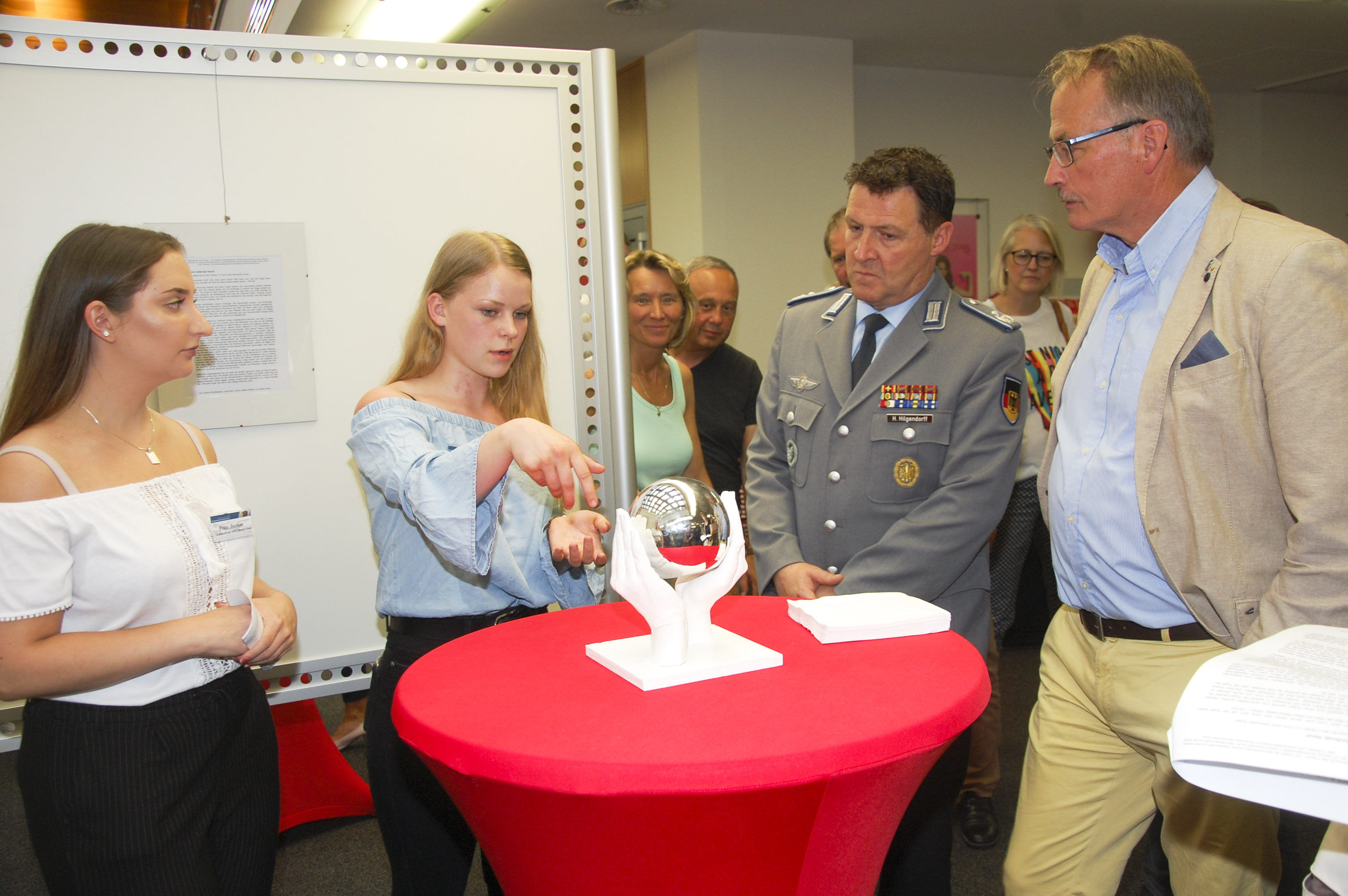 Zwei Schülerinnen erklären den umstehenden Besuchern ihre Idee von der drehbaren Kugel, welche in einer Schale aus Händen liegen soll.